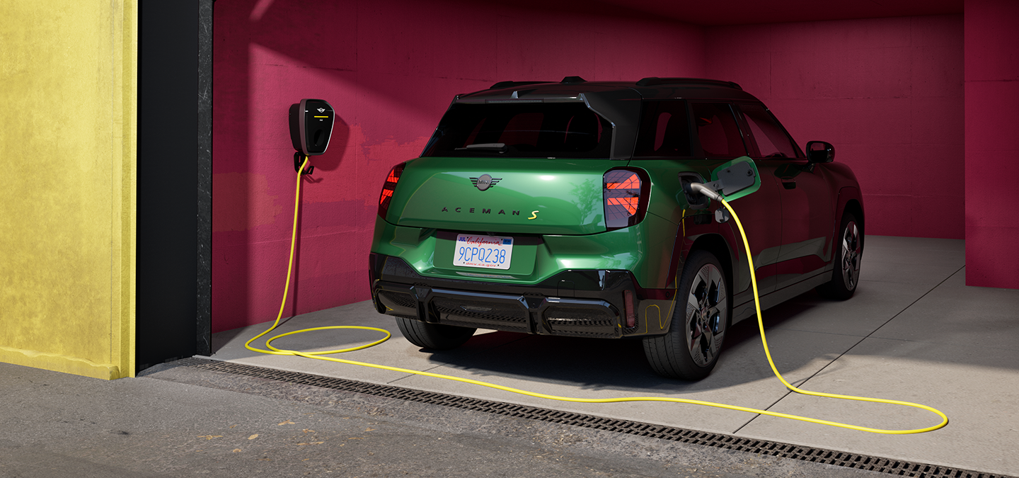 MINI Aceman in British Racing Green IV Metallic charging inside a garage using a wall-mounted charger.