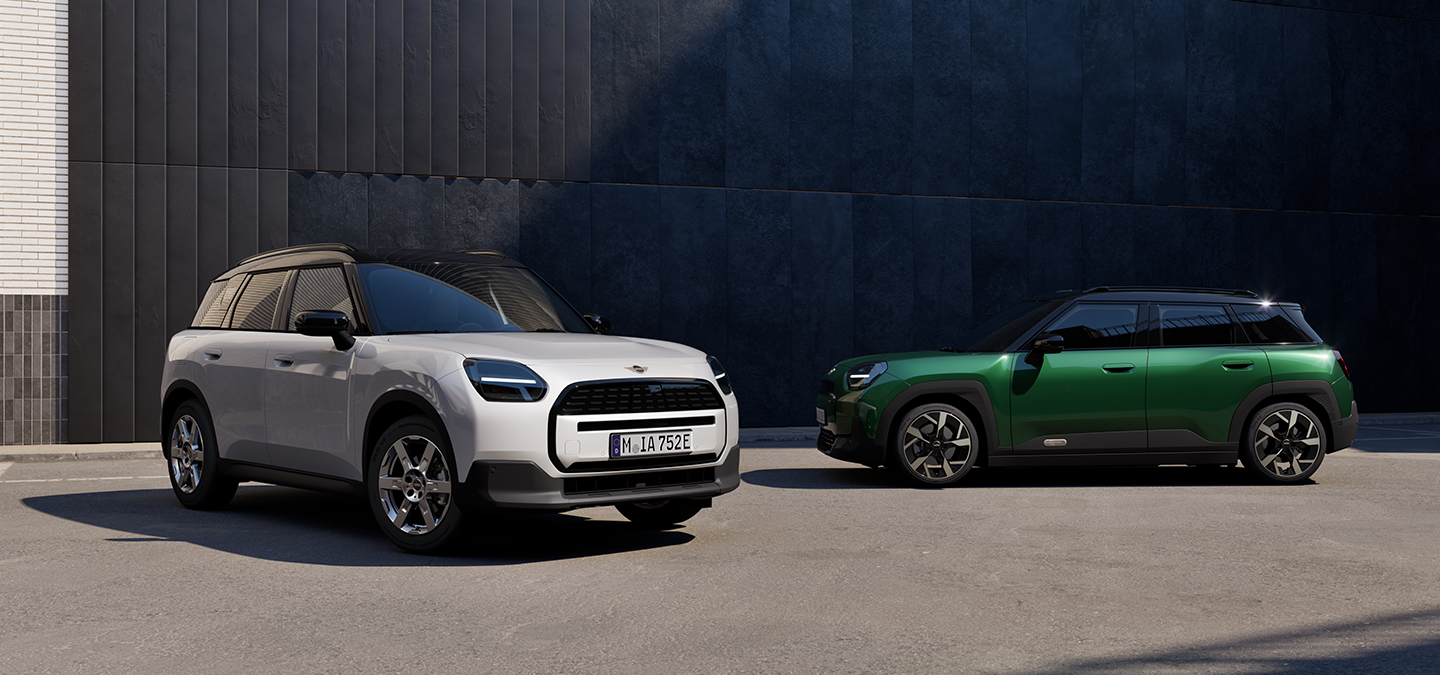 Two MINI Countryman models parked side by side, one in Nanuq White Metallic and one in British Racing Green IV Metallic.