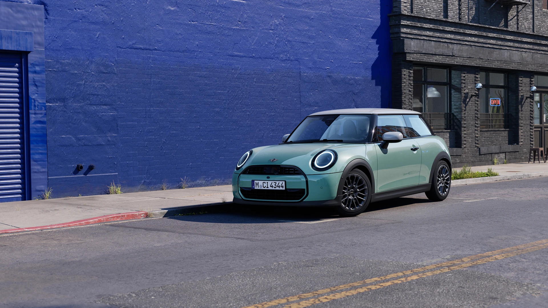 MINI Cooper in Ocean Wave Green parked on an urban street beside a blue wall.