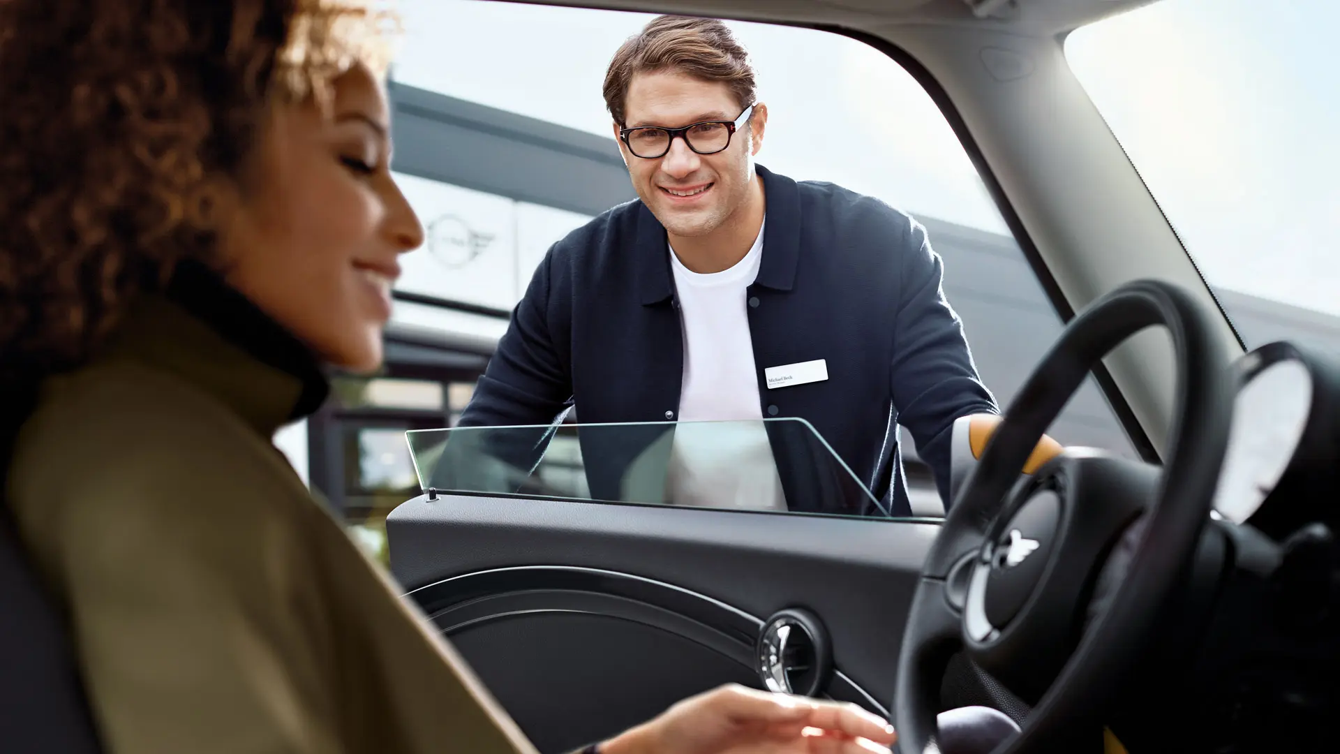 MINI service advisor speaking with a driver inside a MINI vehicle.