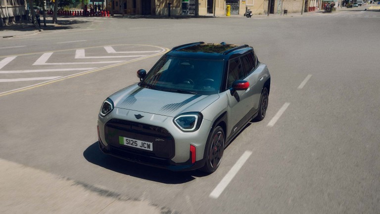 MINI Countryman John Cooper Works in Nanuq White Metallic driving through an urban intersection.